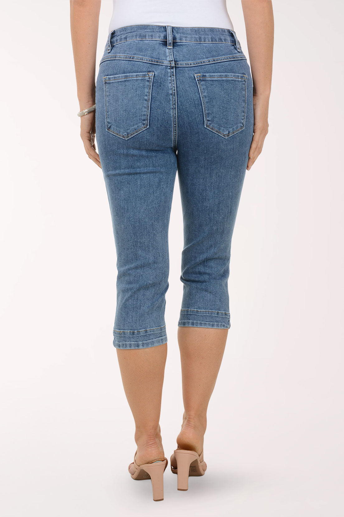 Person wearing blue denim capri pants on a white background