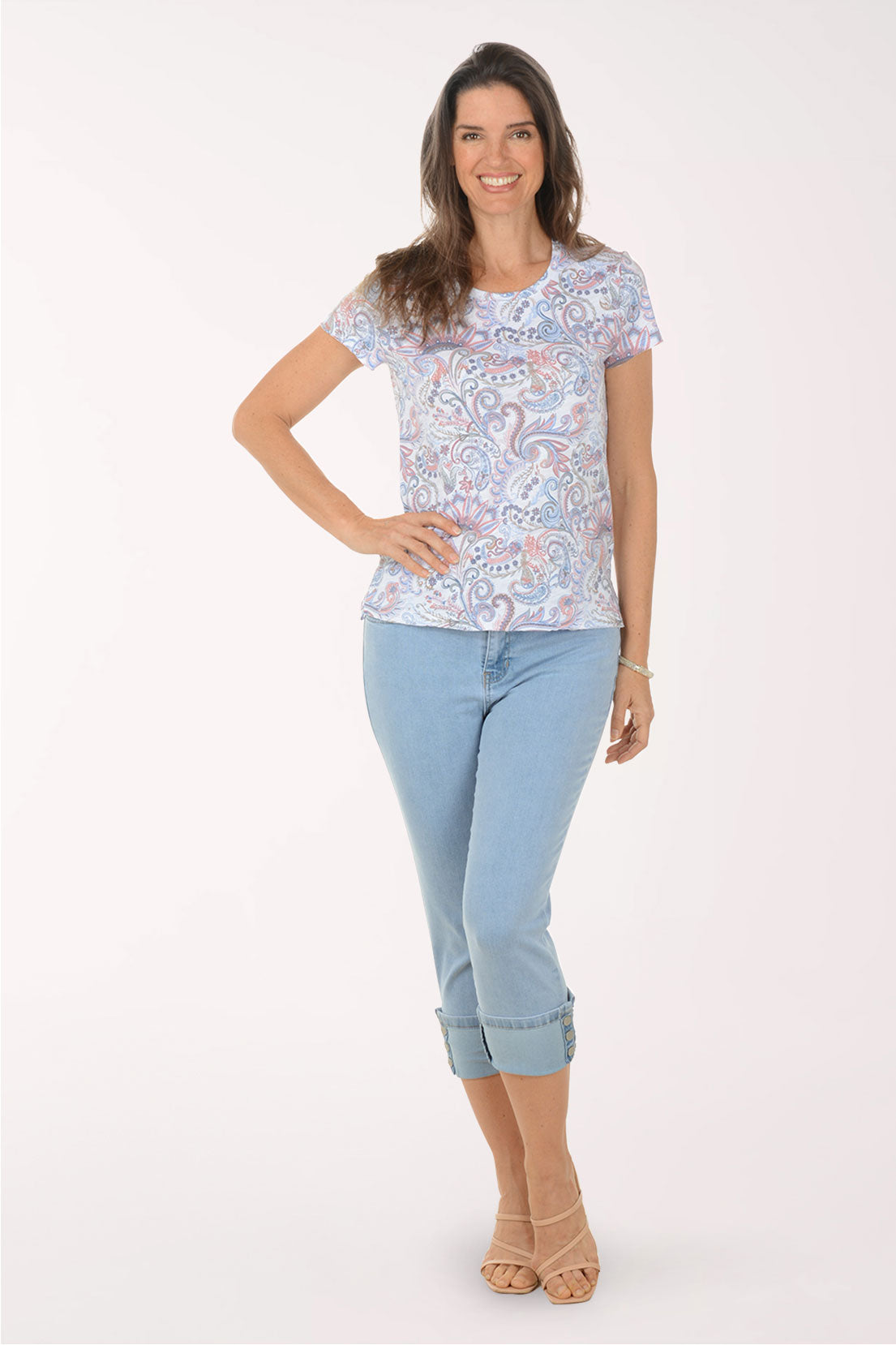Woman wearing a patterned top and light blue jeans on a white background