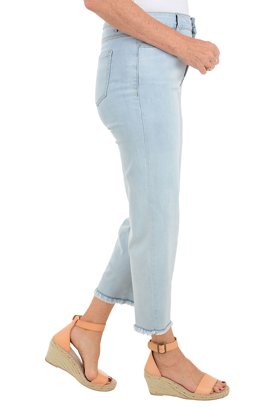 A pair of light blue denim ankle pants with embroidery on the left leg and frayed hemline, displayed on a model wearing tan sandals. Side shot.