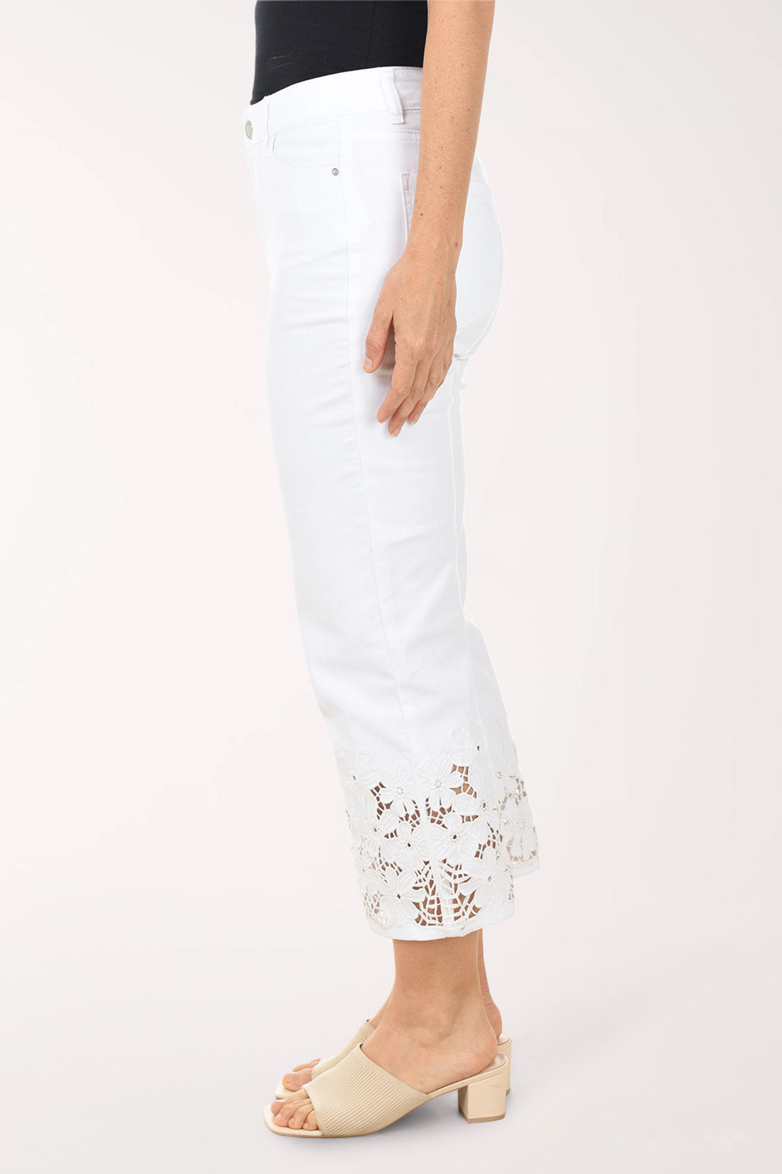Woman wearing a blue and white patterned top with white pants on a white background