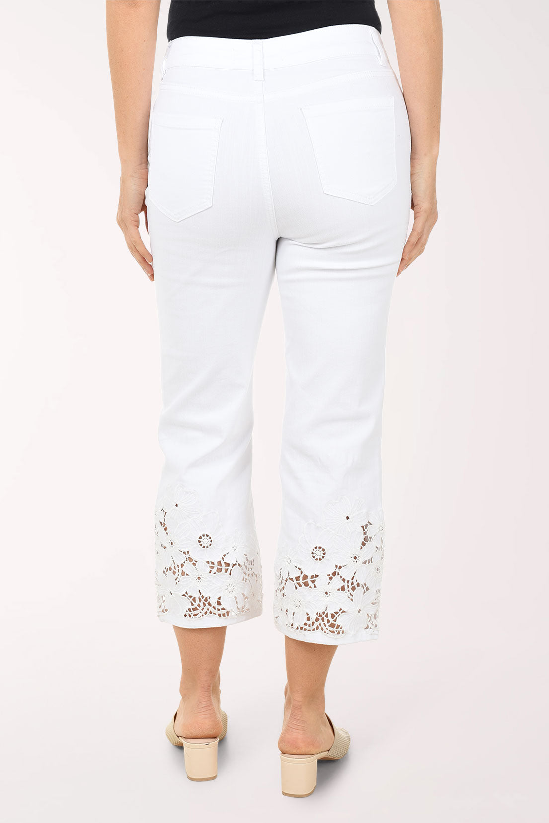Woman wearing a blue and white patterned top with white pants on a white background