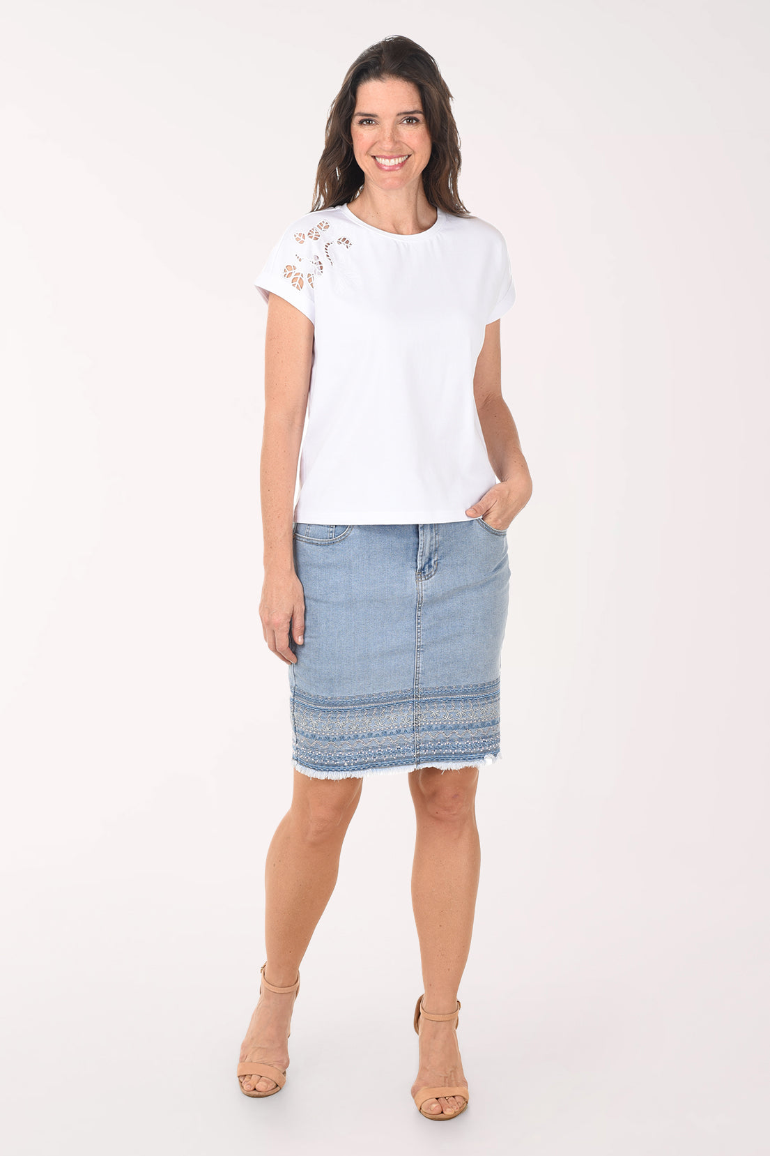 Woman wearing a white t-shirt with lace sleeves and a light blue denim skirt on a white background