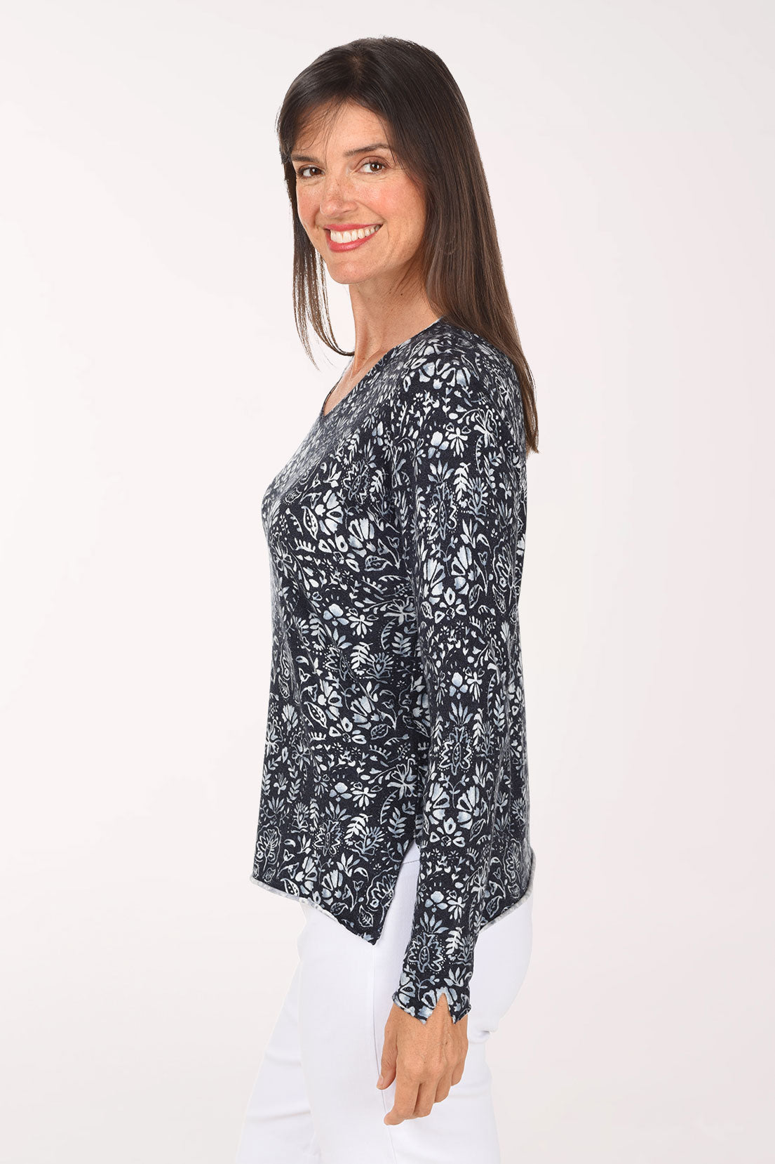 A side view of the navy botanical print sweater showing the rolled hem with side slit.