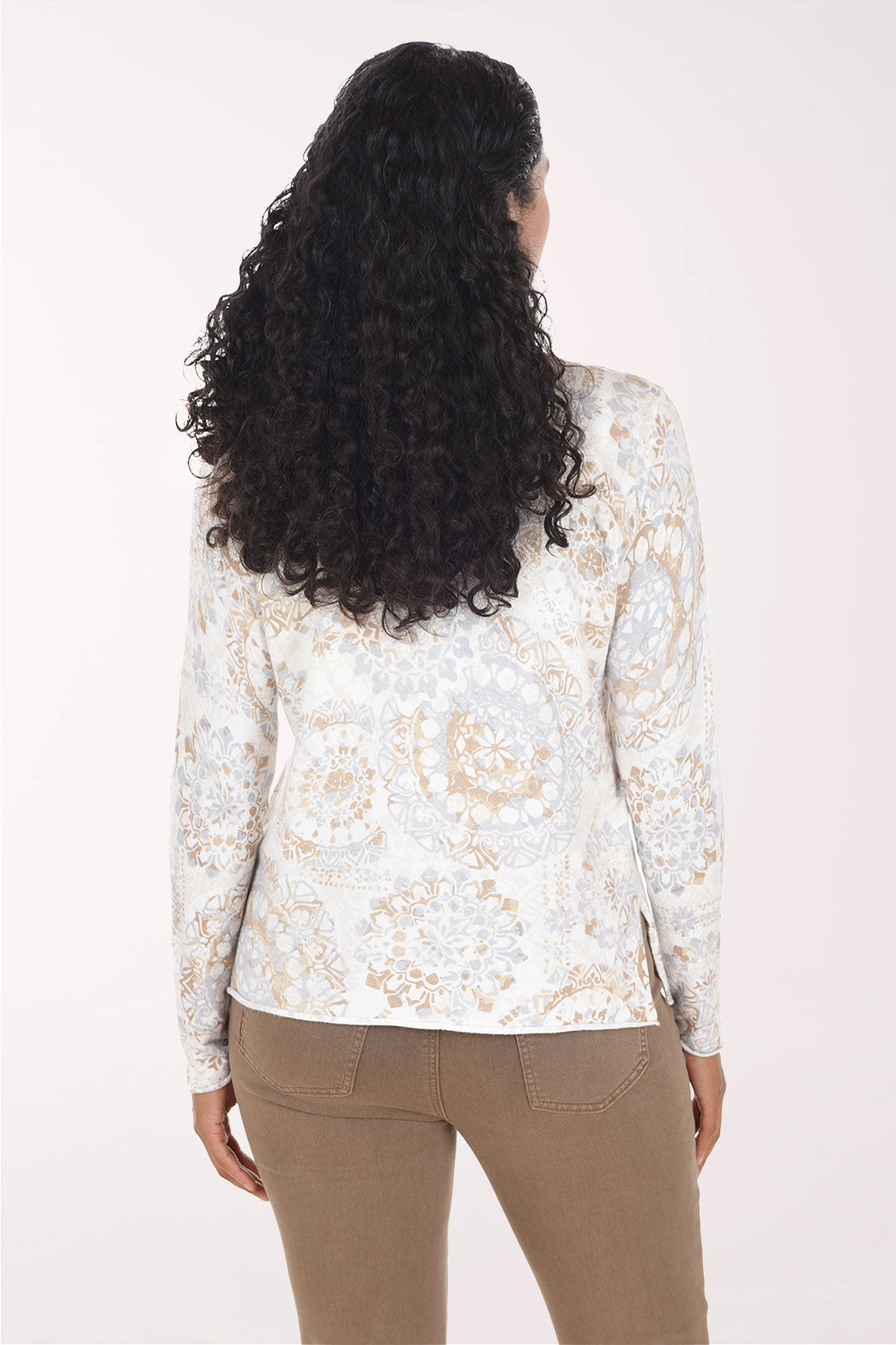 Woman wearing a long sleeve white sweater with a paisley print