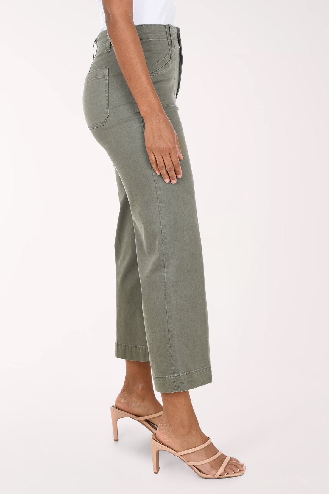 A model wearing olive green cropped wide-leg jeans with a white top and beige heeled sandals, shown from the waist down against a light studio background.