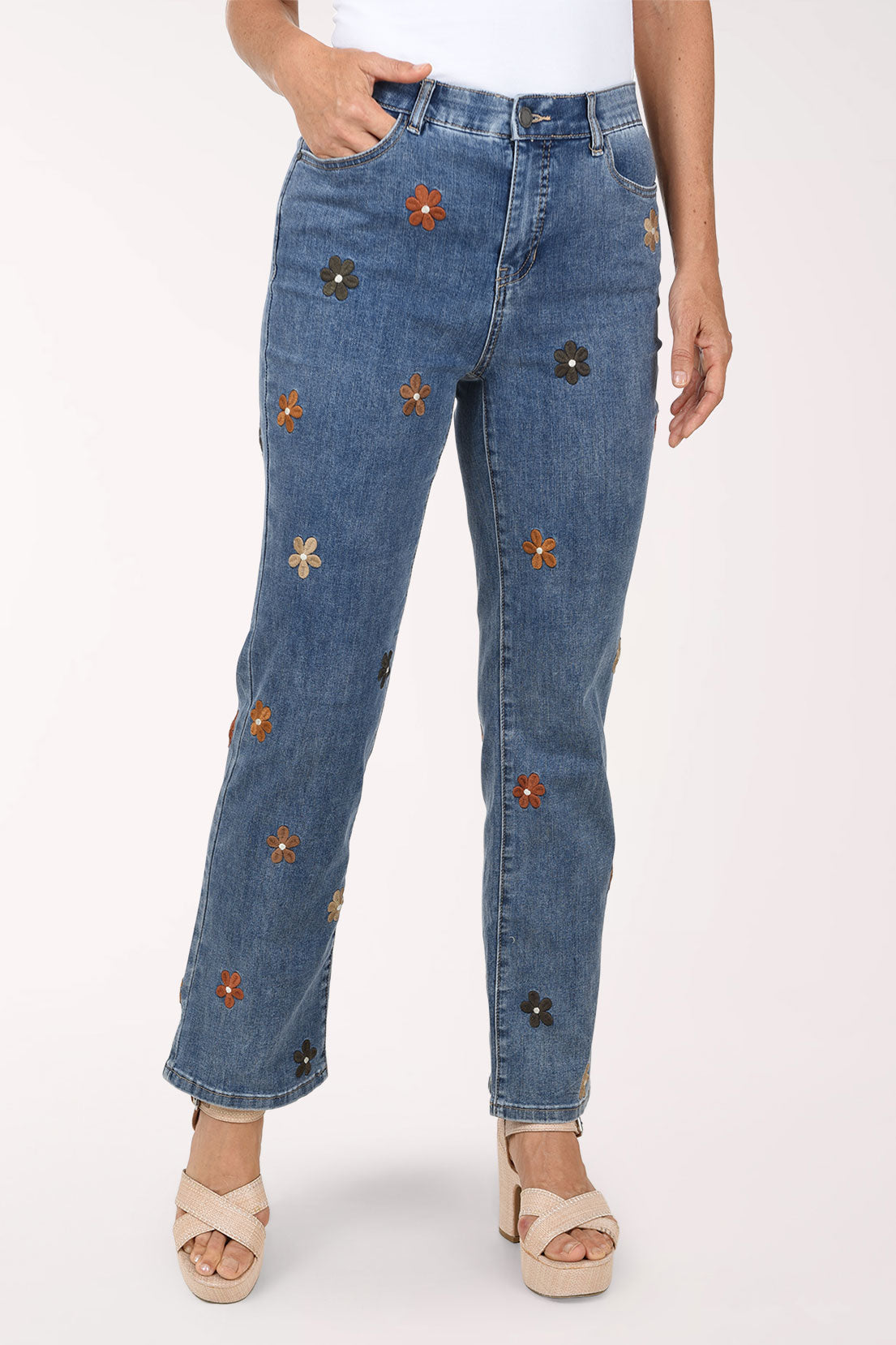 A front view of medium blue straight leg jeans scattered with small embroidered flowers in brown, rust and black.