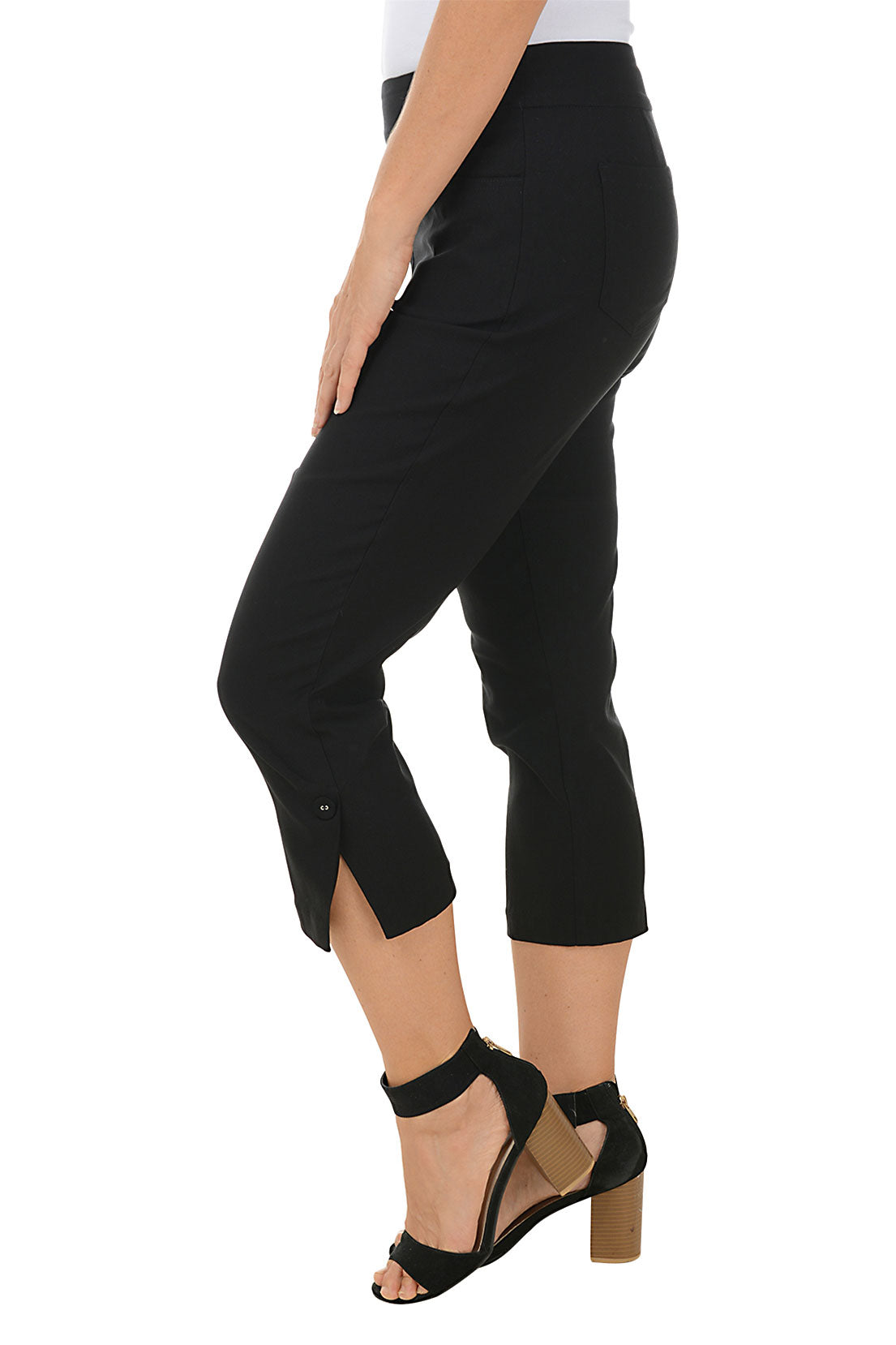 A model wearing black pull-on capri pants with an elasticized waistband, dual front and back pockets, and fabric-covered buttons at the hemline. Side shot.