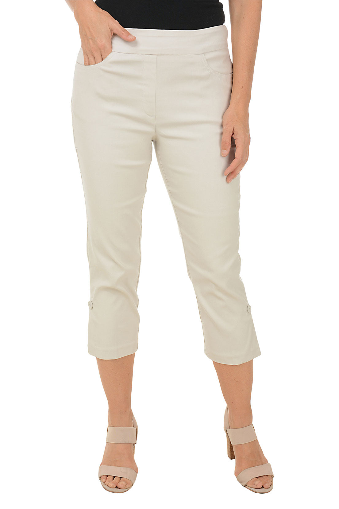 A model wearing beige pull-on capri pants with an elasticized waistband, dual front and back pockets, and fabric-covered buttons at the hemline.