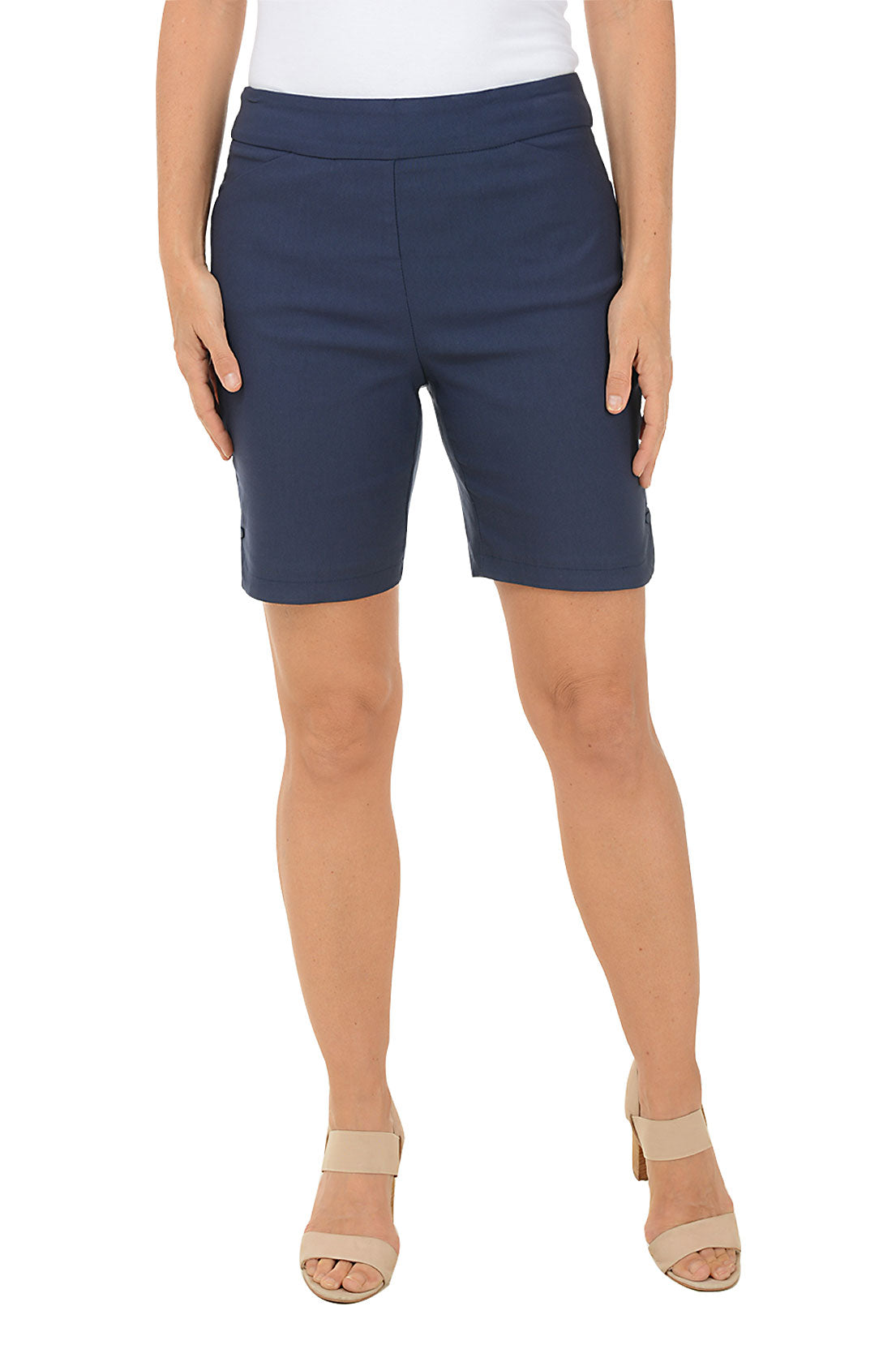 A model wearing navy pull-on shorts with a 2-inch elasticized waistband, dual front pockets, and a curved tulip hemline with snap button detail.