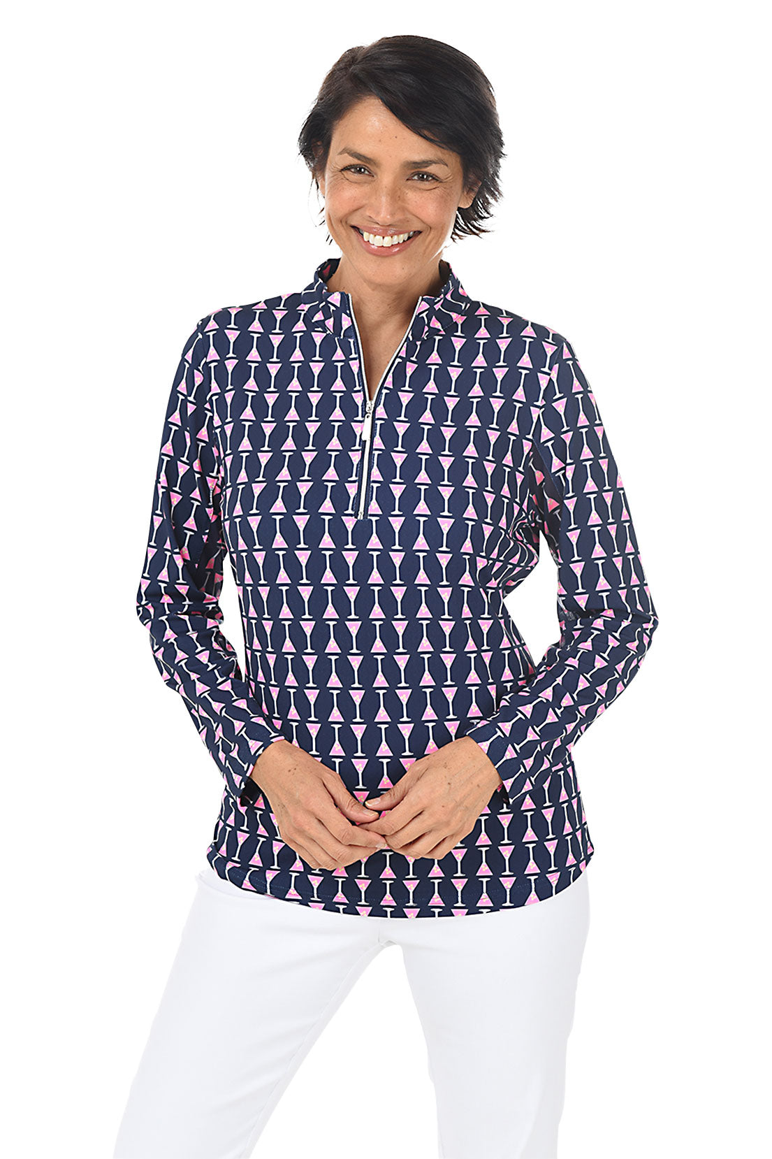 A woman wearing a long sleeve navy mock neck top with a martini glass pattern, paired with white pants.