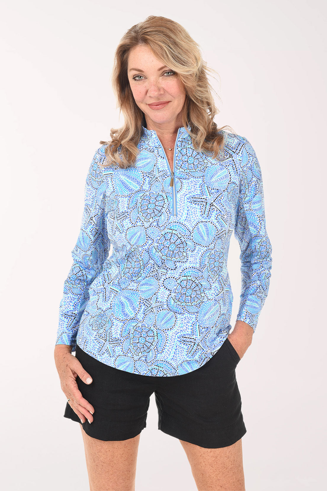 Woman wearing a blue patterned long-sleeve shirt and black shorts on a white background