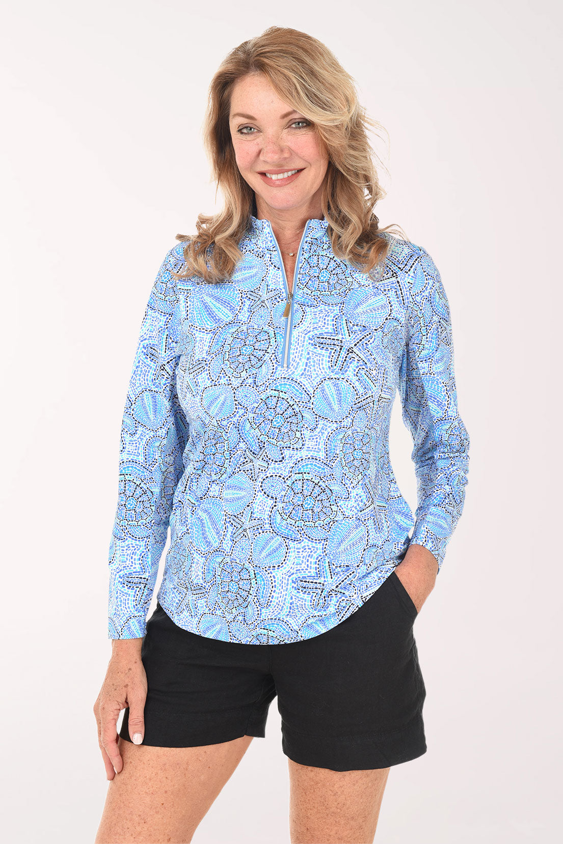 Woman wearing a blue patterned long-sleeve shirt and black shorts on a white background