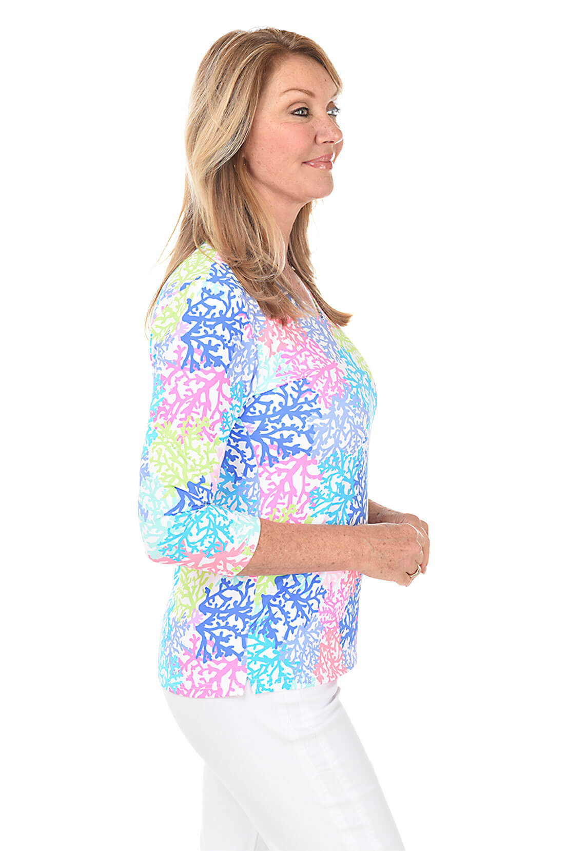 A woman wearing a multicolored coral patterned V-neck top with 3/4 sleeves. Side shot.
