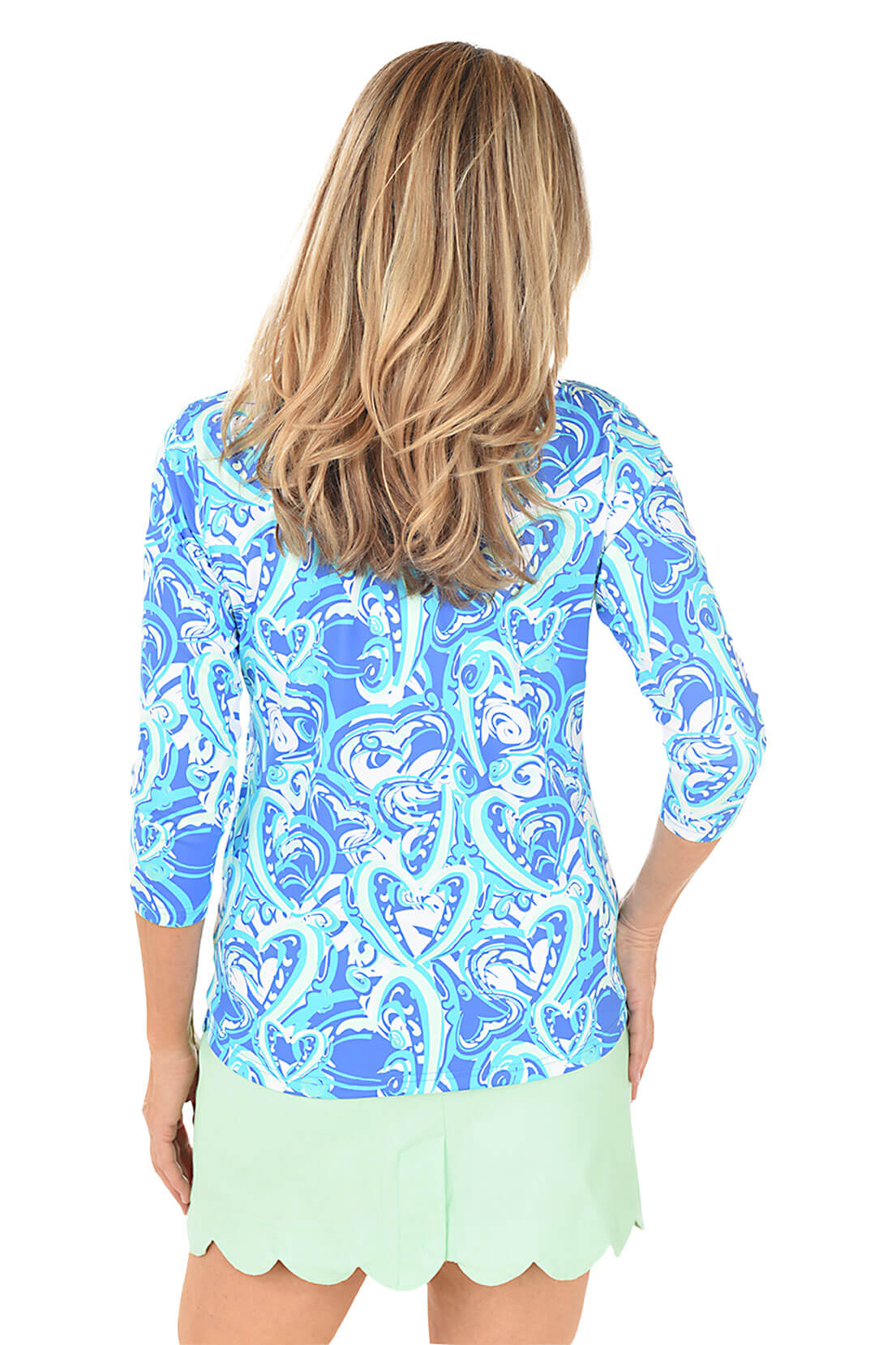 A woman wearing a blue heart patterned v-neck top with 3/4 sleeves. Back shot.