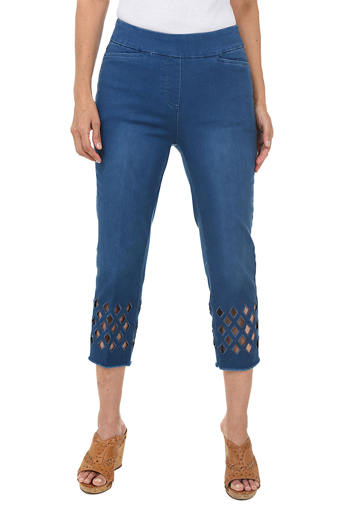 A woman wearing cropped denim pants with diamond-shaped eyelet cut-outs near the frayed hem.