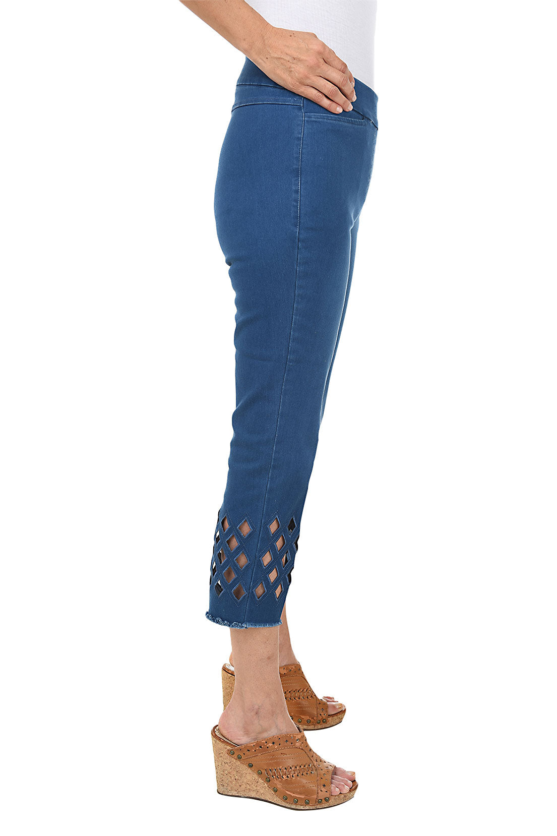 A woman wearing cropped denim pants with diamond-shaped eyelet cut-outs near the frayed hem. Side shot.
