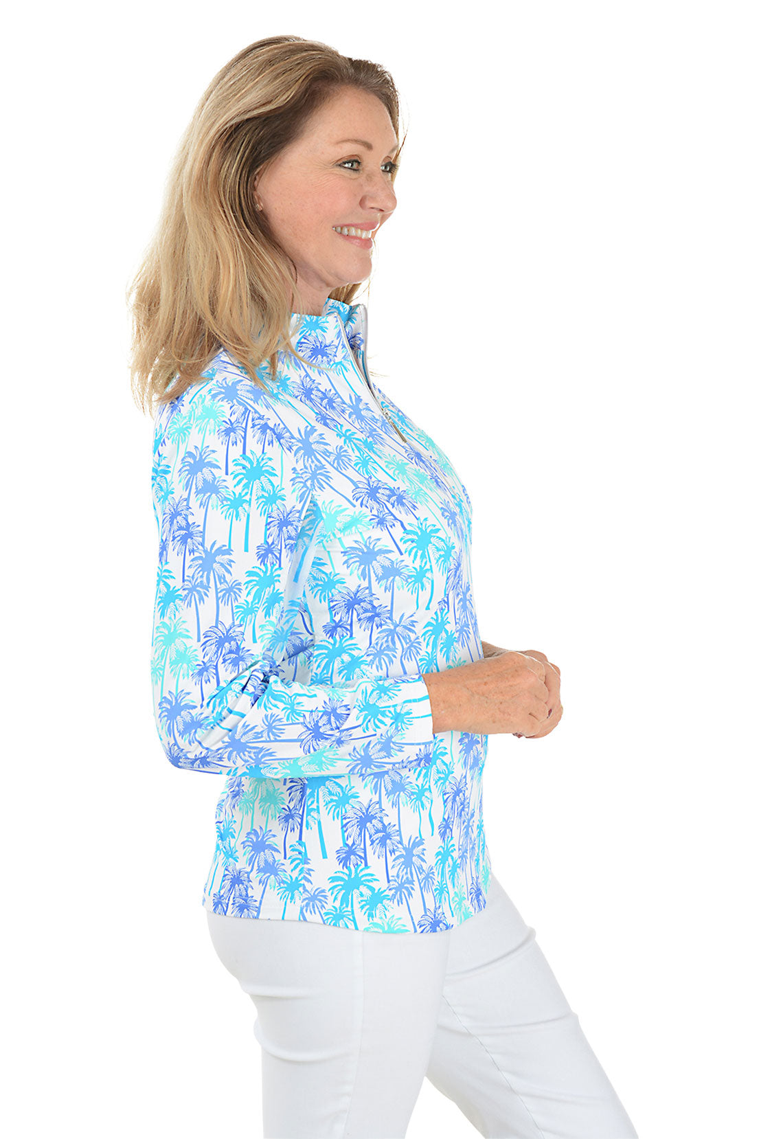 A woman wearing a long sleeve sun shirt with a mock neckline and a palm tree pattern in blue and white colors. Side shot.