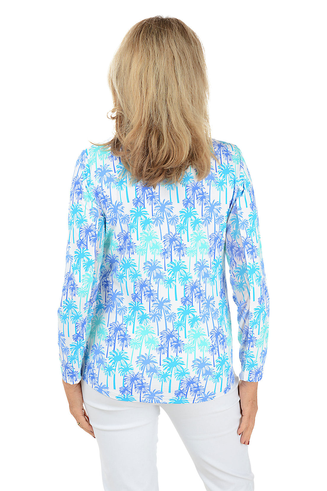 A woman wearing a long sleeve sun shirt with a mock neckline and a palm tree pattern in blue and white colors. Back shot.