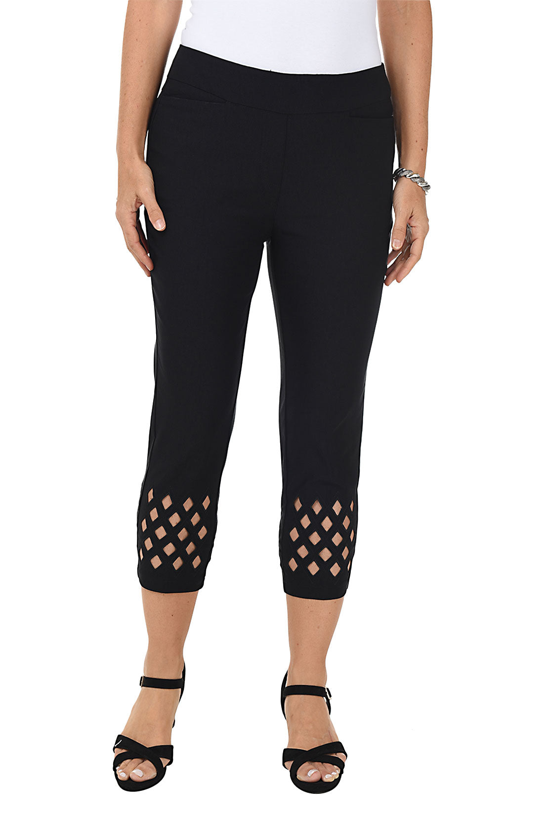 A woman wearing black cropped trousers with diamond eyelet cut-outs at the hem.