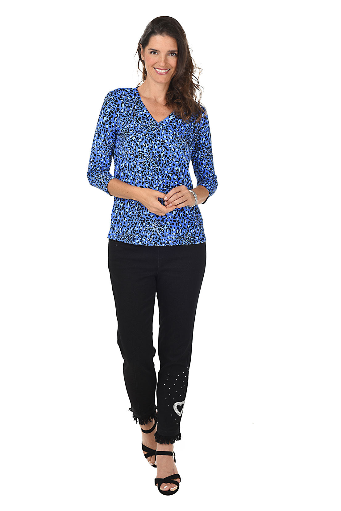 A woman wearing black denim ankle length jeans with a heart-shaped rhinestone applique and frayed hemline. Full length shot.