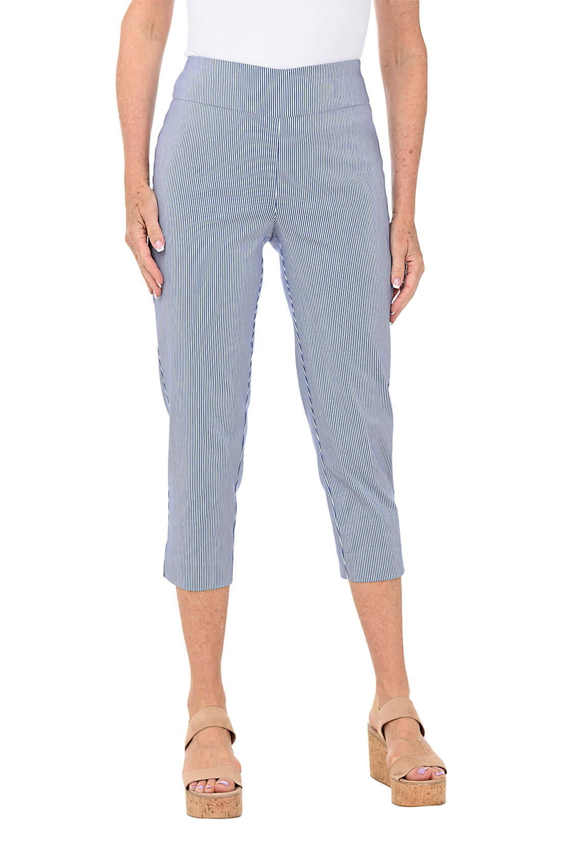 A front shot of a model wearing a pair of petite striped pull-on capri pants in a light color, possibly blue, with the person wearing them standing against a plain background.
