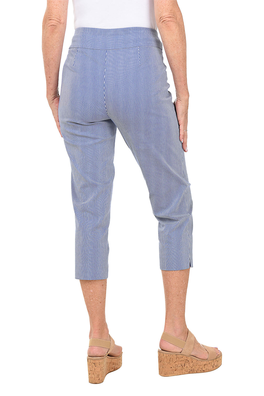 A back shot of a model wearing a pair of petite striped pull-on capri pants in a light color, possibly blue, with the person wearing them standing against a plain background.