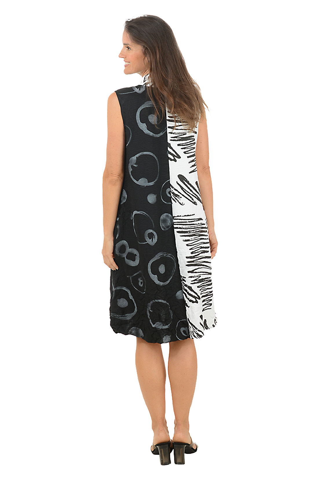 Woman wearing a sleeveless dress with black and white abstract pattern on a white background