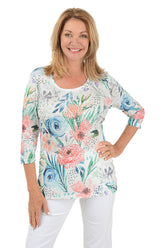 A woman wearing a multicolored floral knit top with a scoop neck and 3/4 sleeves. The top appears to be lightweight and has rhinestone embellishments.