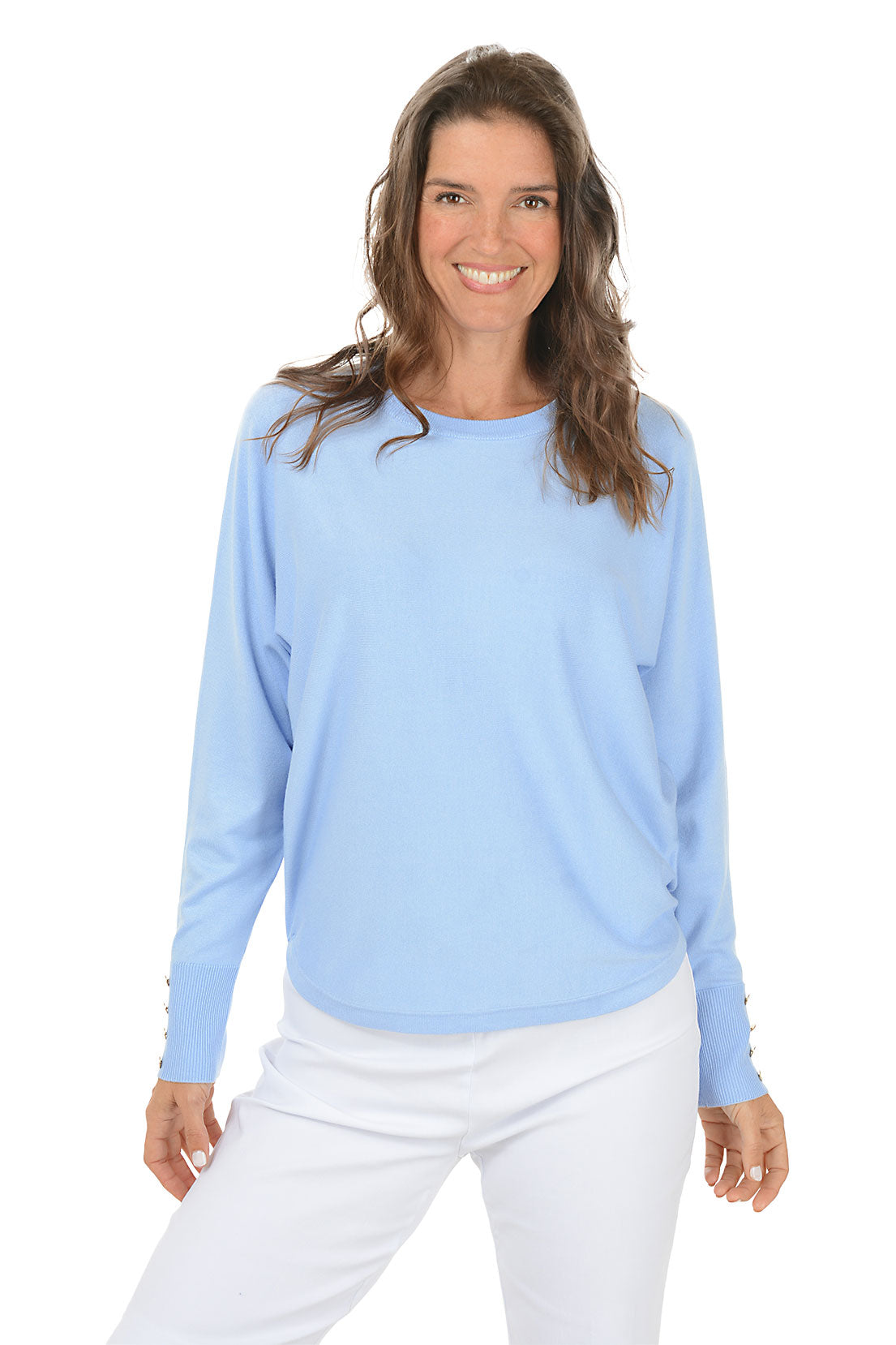 Woman wearing a light blue sweater and white pants on a white background.
