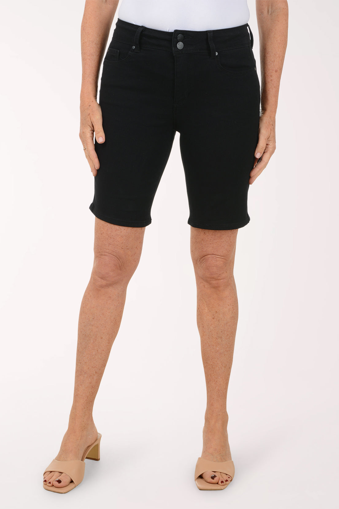 Person wearing black denim shorts on a white background