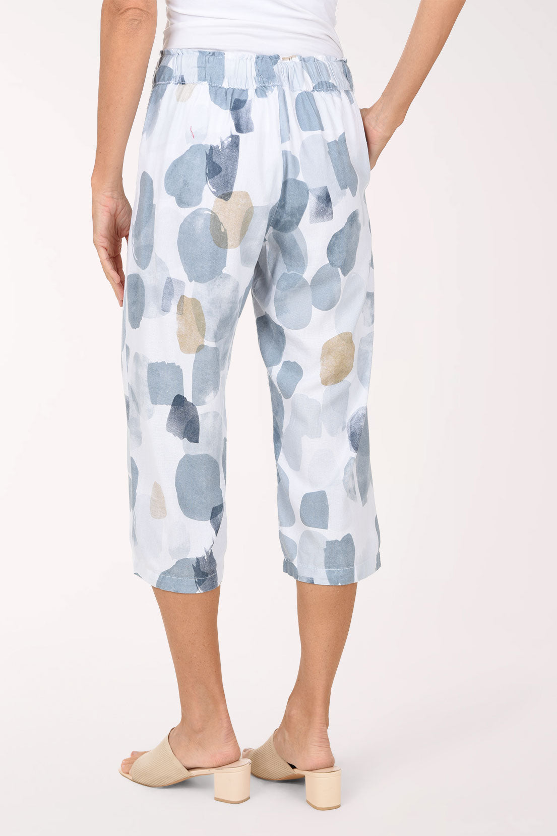 Woman wearing white crop pants with a blue and beige stone pattern