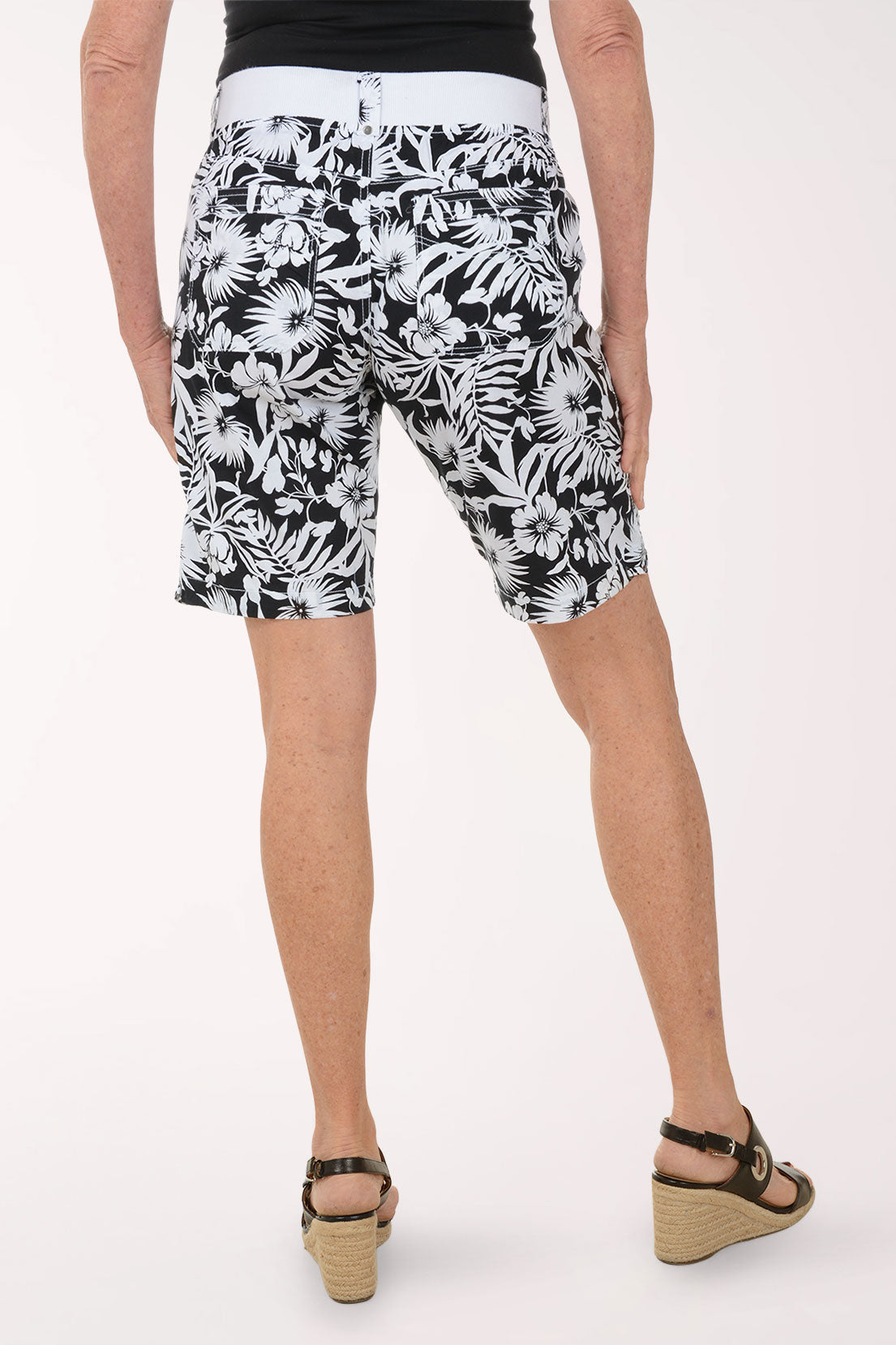 Person wearing black and white floral shorts on a white background