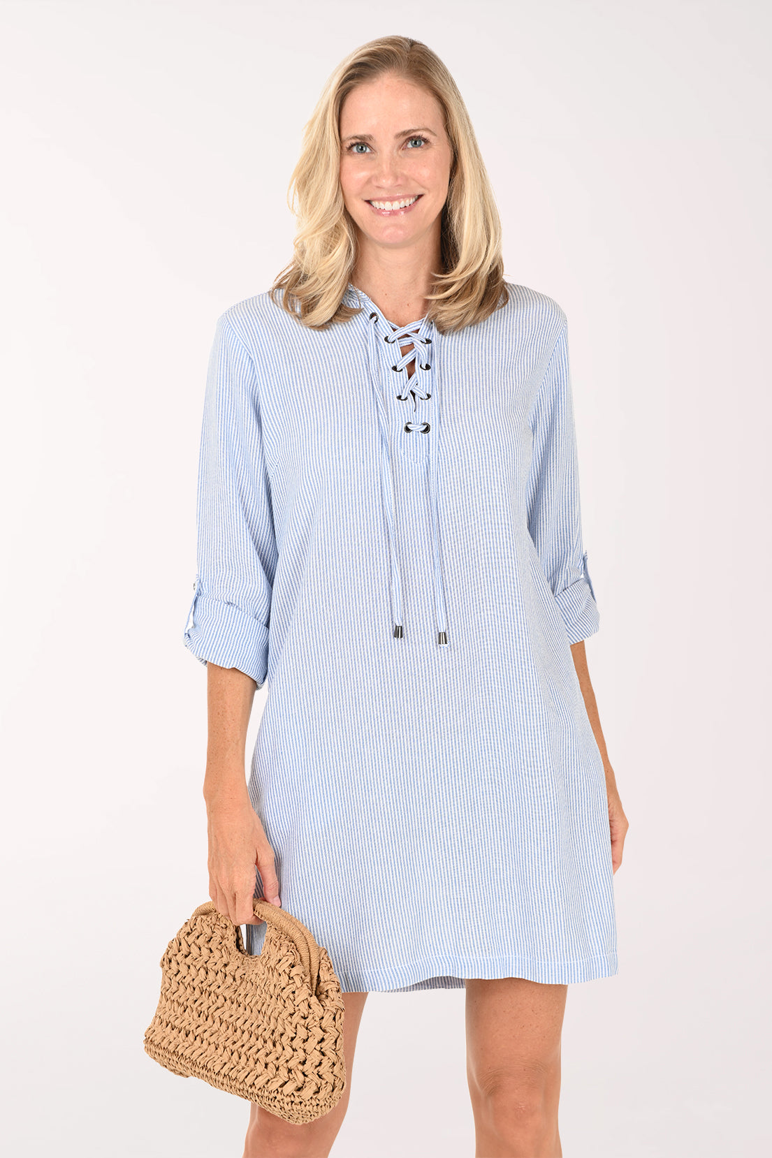 Woman wearing a light blue dress with rolled-up sleeves on a white background