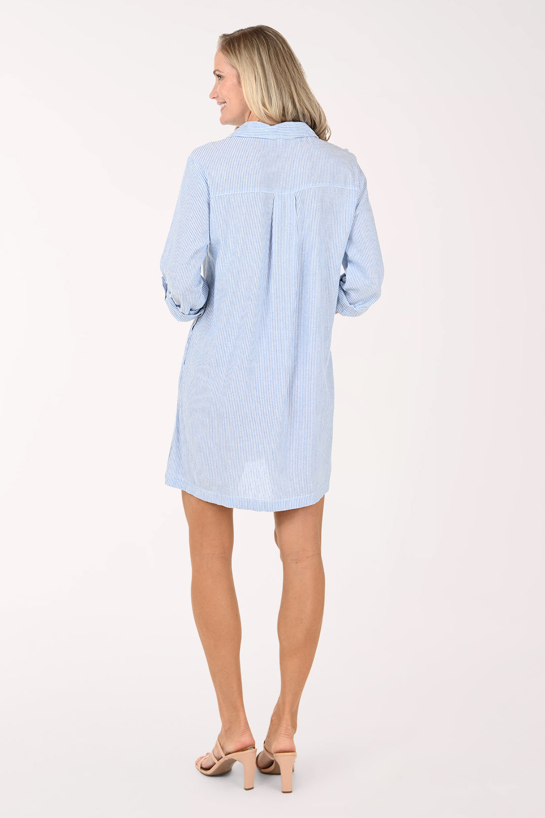 Woman wearing a light blue dress with rolled-up sleeves on a white background