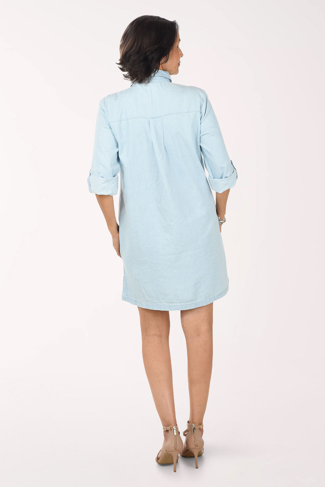 Woman wearing a light blue dress with lace details on a white background