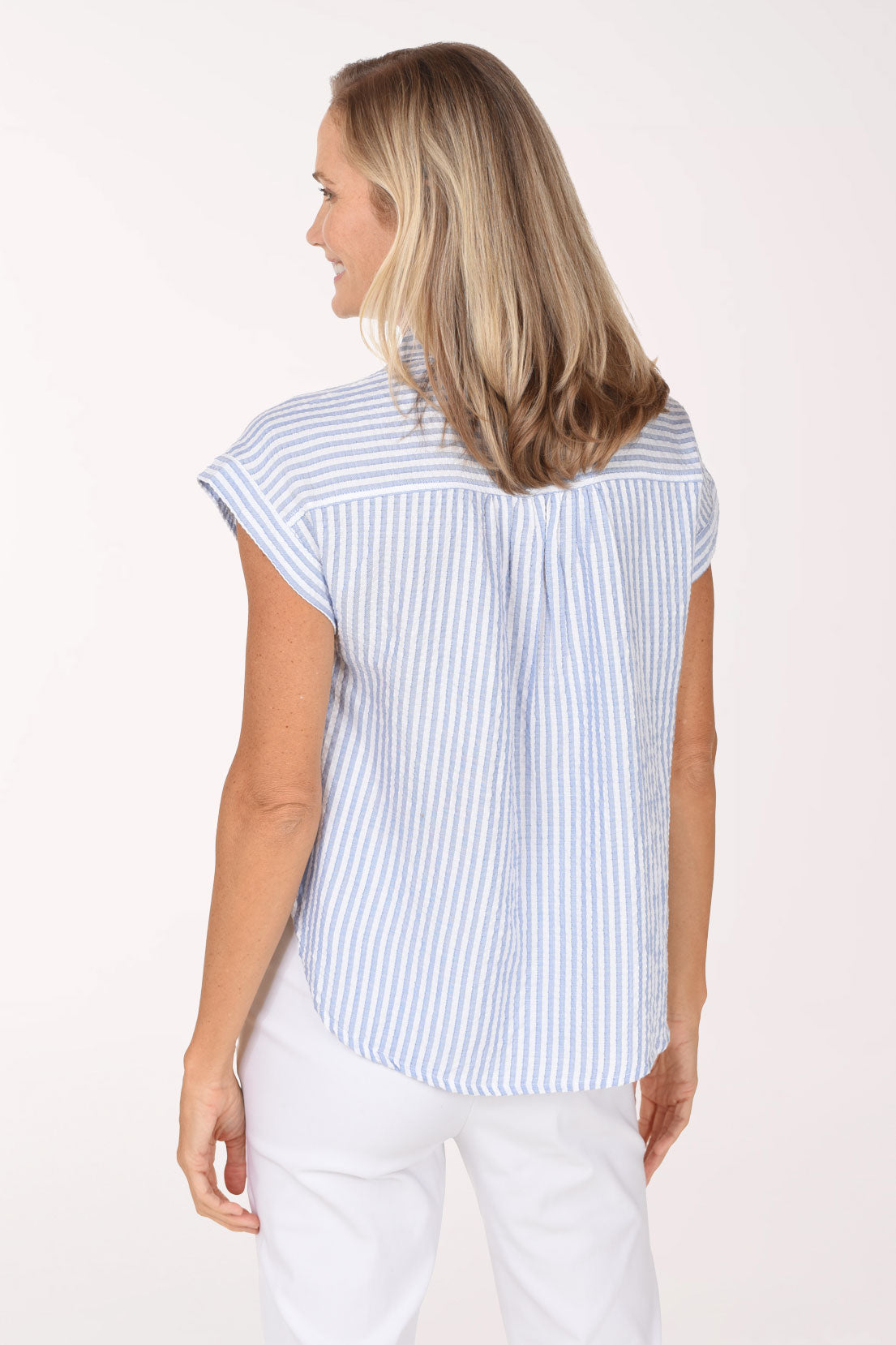 Woman wearing a cap sleeve button up shirt with a seersucker blue and white stripe pattern
