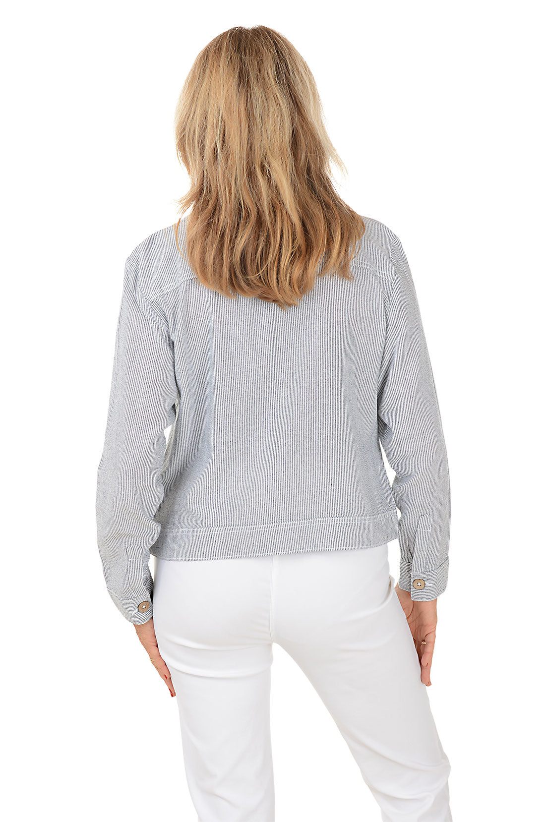 A back shot of a model wearing a gray denim jacket over a black top and white pants on a white background