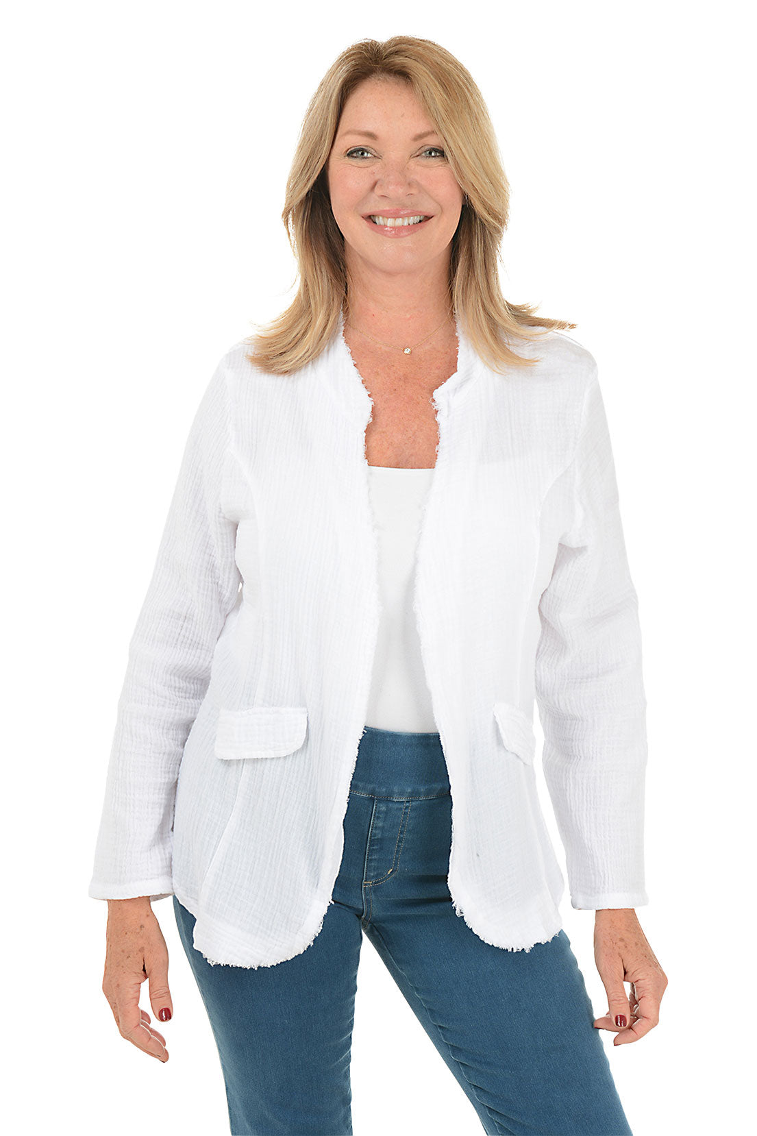 A smiling blonde woman wearing a white textured open-front jacket with scalloped edges over a white top and blue jeans, photographed against a plain white background.