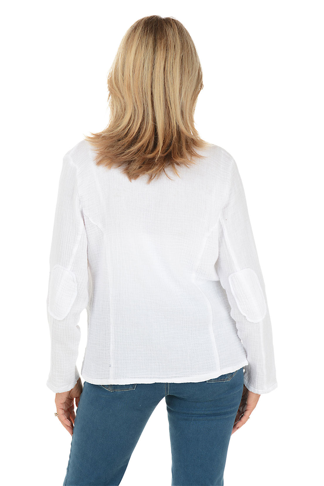 A smiling blonde woman wearing a white textured open-front jacket with scalloped edges over a white top and blue jeans, photographed against a plain white background.
