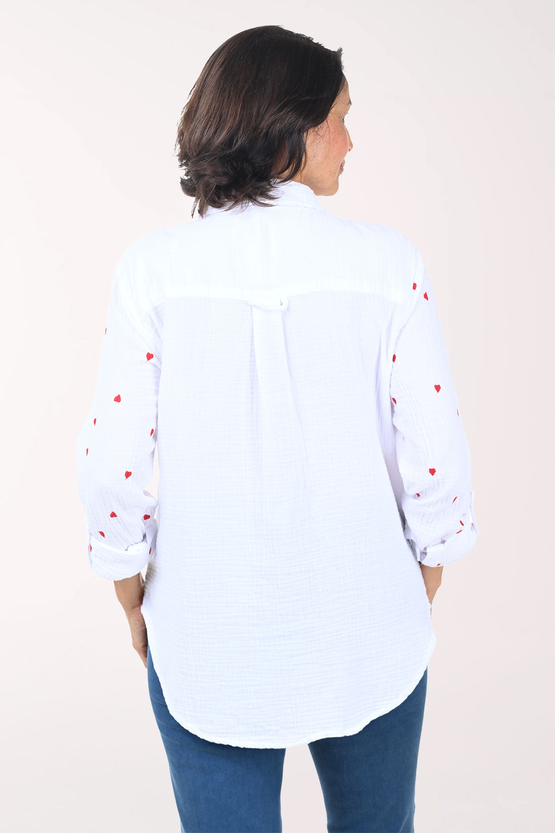 Woman wearing a white button down shirt with embroidered hearts