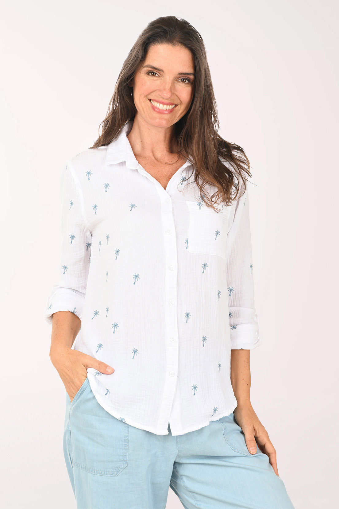 Woman wearing a 3/4 sleeve white top with embroidered palm trees