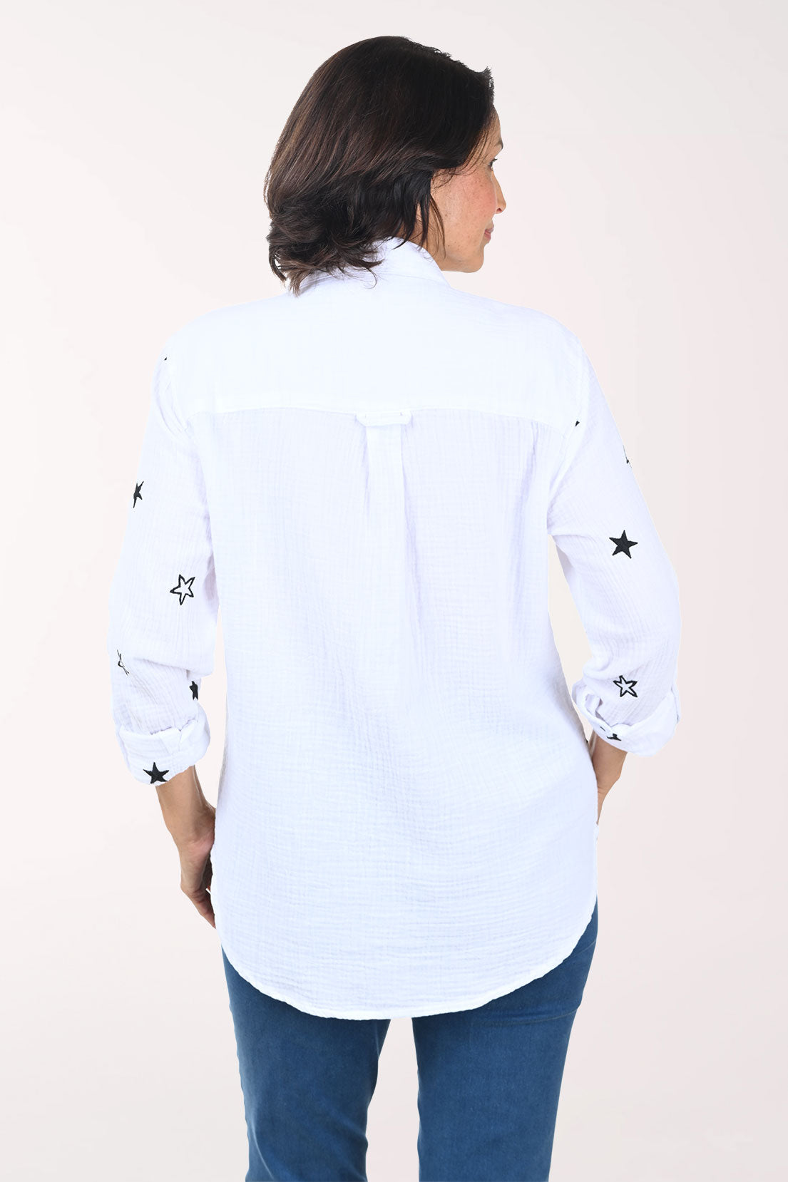 Woman wearing a white shirt with black star patterns on a plain background