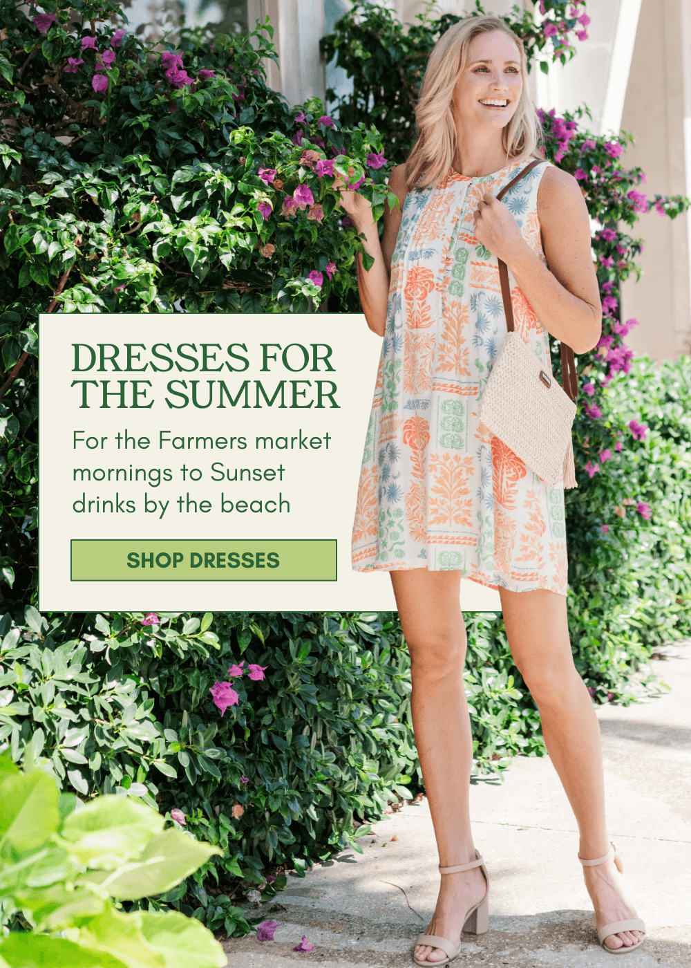 A woman wearing a sleeveless, knee-length dress with a colorful geometric pattern stands outdoors in front of green foliage and pink flowers. A text box on the left reads 'Dresses for the Summer' with descriptive copy and a 'SHOP DRESSES' button.