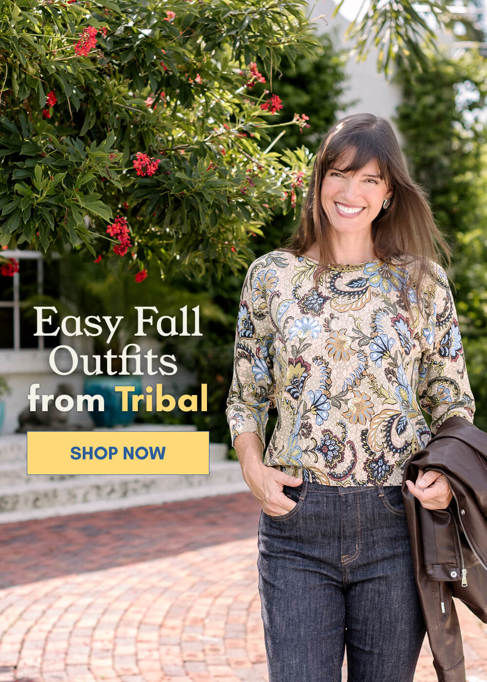 Mobile version of our model wearing a colorful floral print Tribal top with dark denim jeans, holding a brown jacket outdoors. Shop easy fall outfits from Tribal at Anthony's.