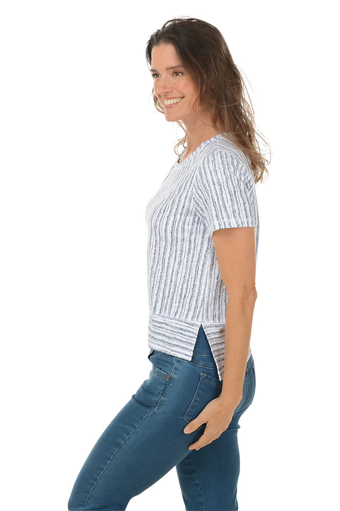 A woman wearing a striped high-low hemline t-shirt with a scoop neckline and short sleeves. Side shot.