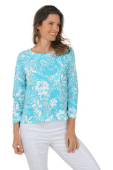 A woman wearing a blue and white paisley scroll 3/4 sleeve knit top with a scoop neckline and high-low hemline.