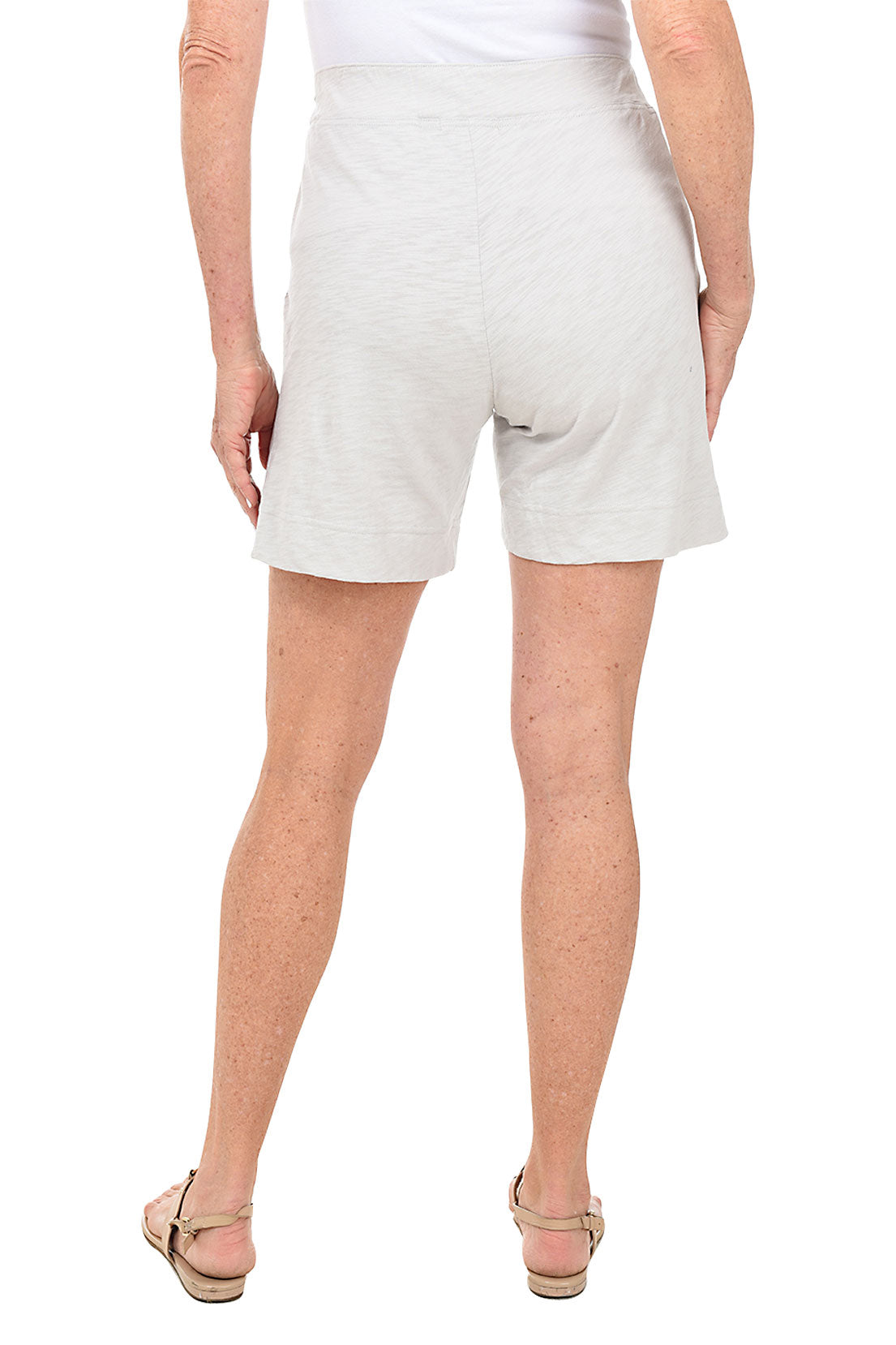 Person wearing light grey shorts on a white background. Back shot.