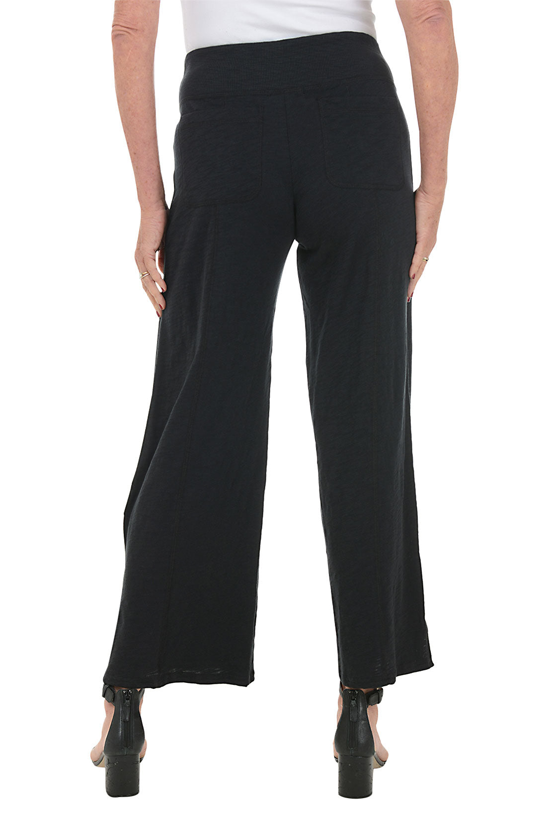 A model wearing black ankle-length pull-on pants with a ribbed waistband and dual back patch pockets. Back shot.