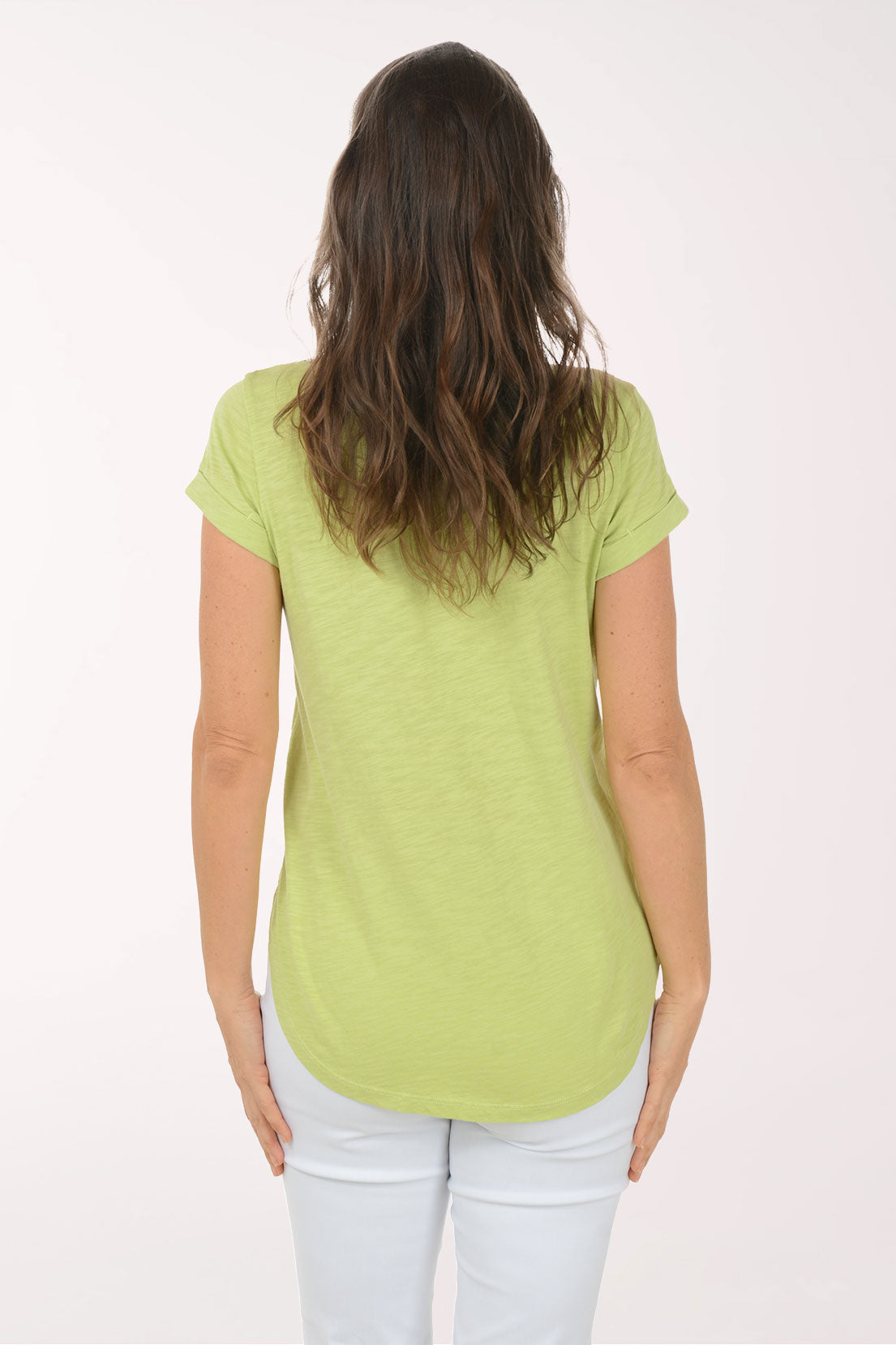 Woman wearing a green t-shirt and white pants on a white background