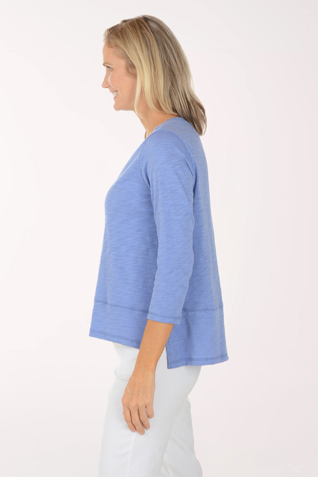 Woman wearing a blue sweater and white pants on a white background